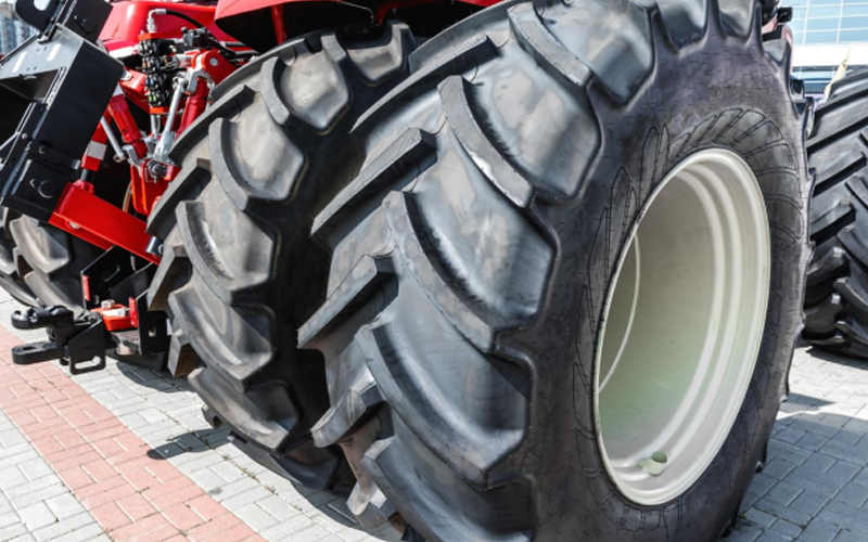 Gros plan de pneus de tracteur avec des bandes de roulement profondes sur un chemin en brique.