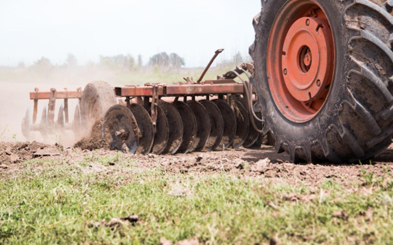 Gros tracteur équipé de pneus à forte bande de roulement engagé dans la culture des terres.