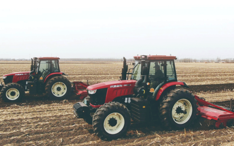 Deux tracteurs FMWorld rouges labourent le champ.