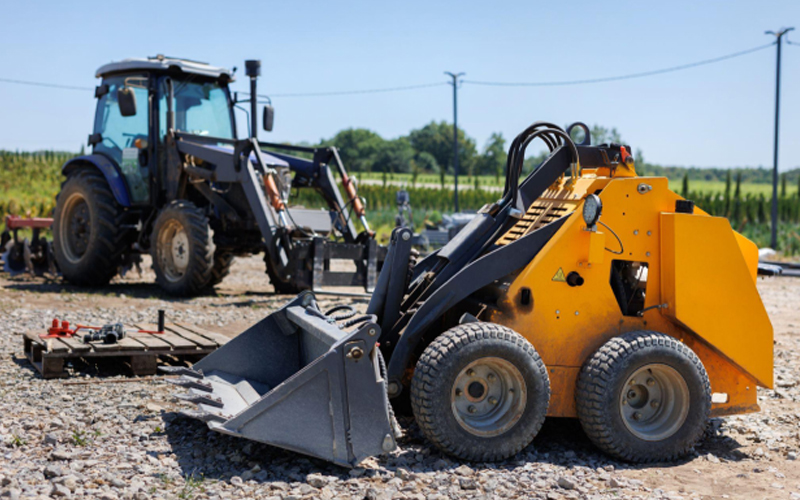 Un petit tracteur avec un godet pour déplacer la terre, le gazon et les matériaux en vrac